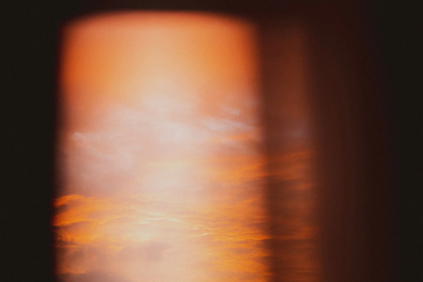 Hazy orange wildfire smoke glowing through a window at dusk
