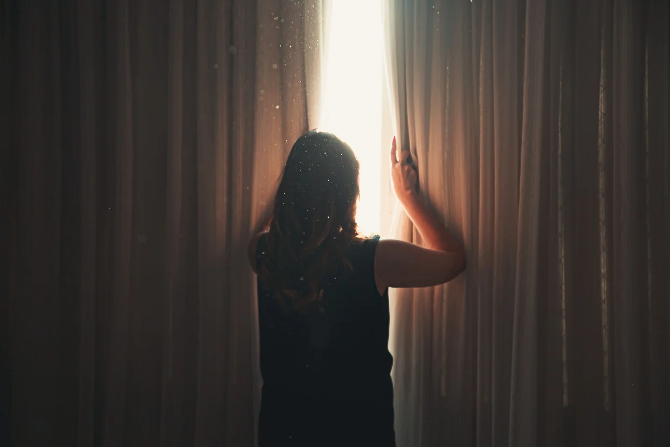 Silhouette by a window with dust particles floating in sunlight