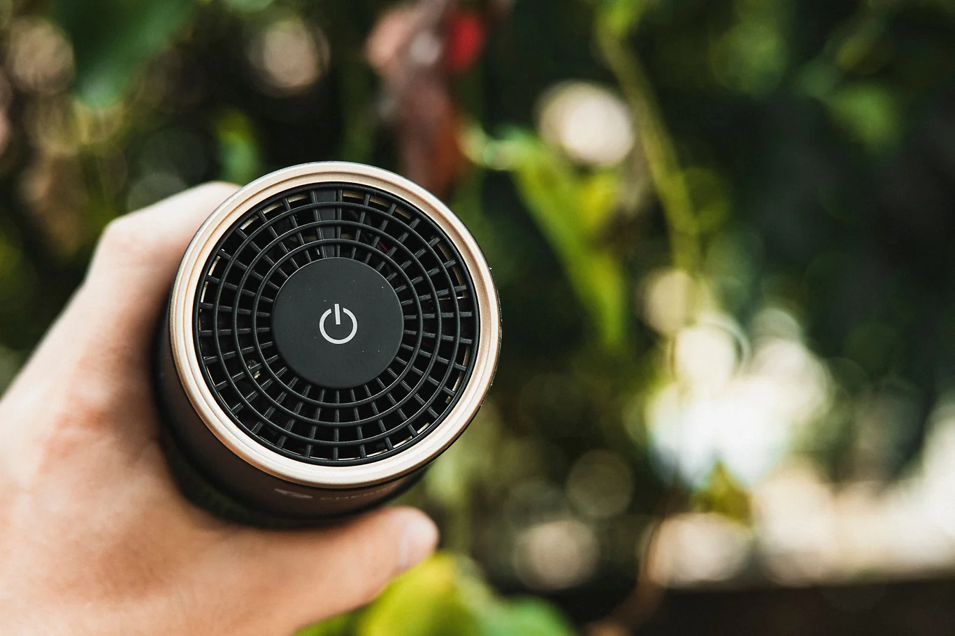 Hand holding a small cylindrical air purifier device