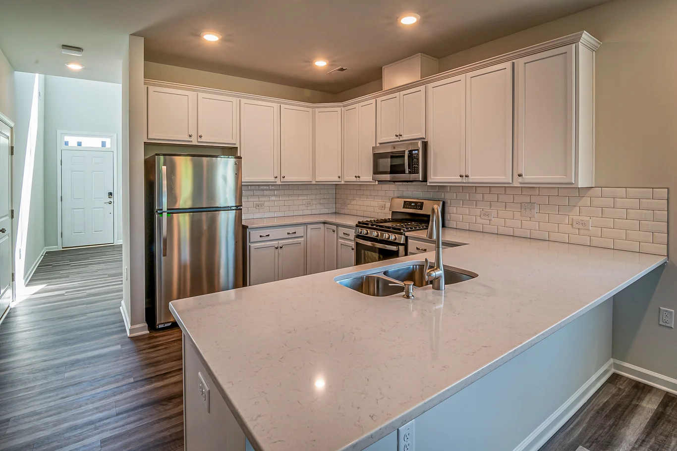 Bright white kitchen with a stainless steel refrigerator