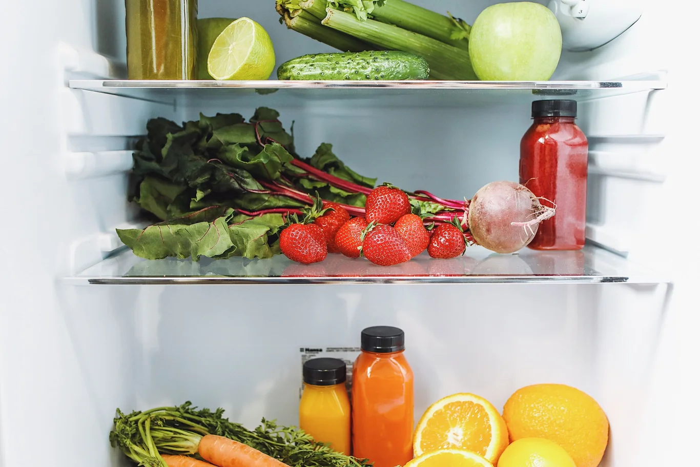 Inside a refrigerator with produce and drinks stored on the shelves