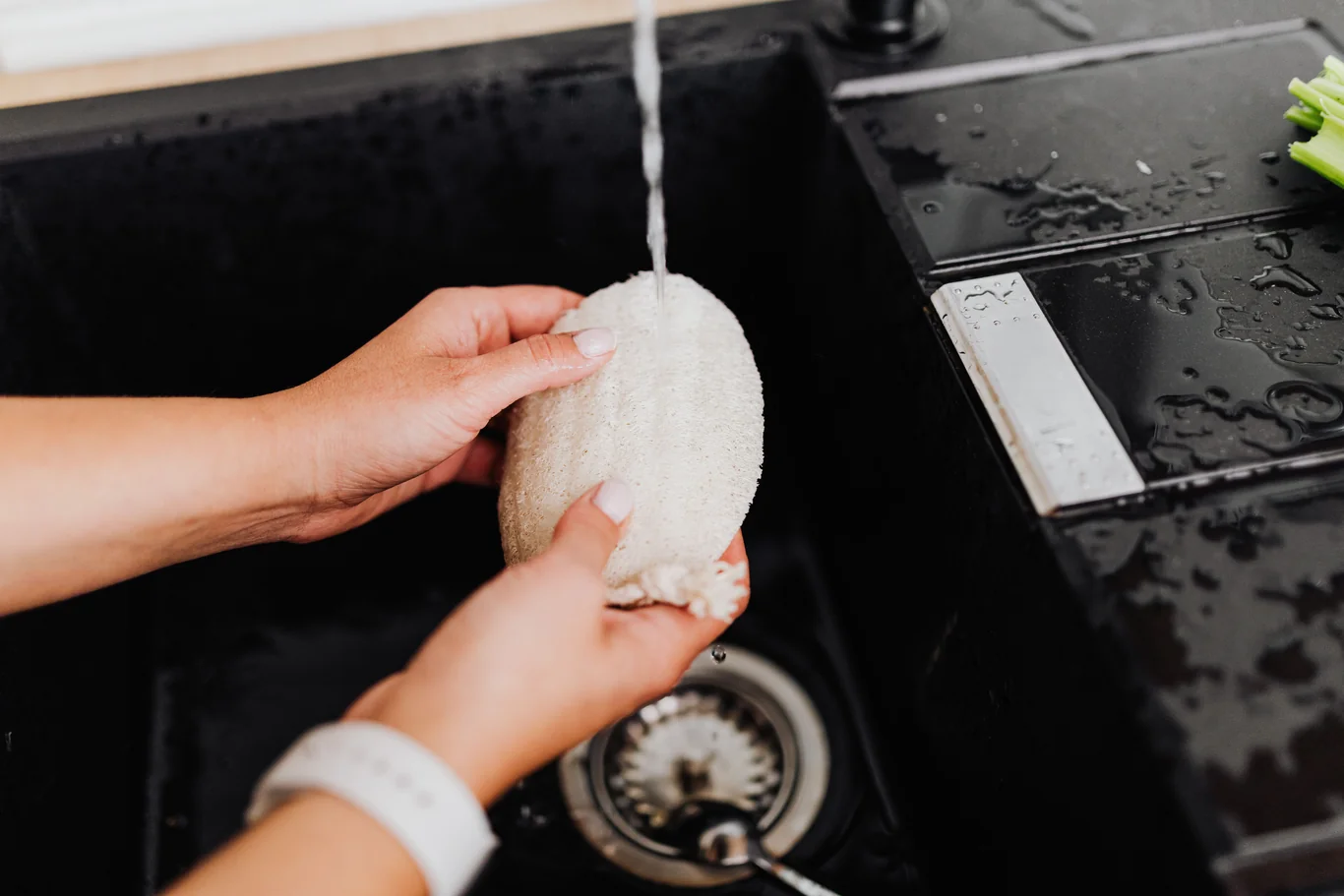 Hand rinsing a foam filter piece under running kitchen faucet water