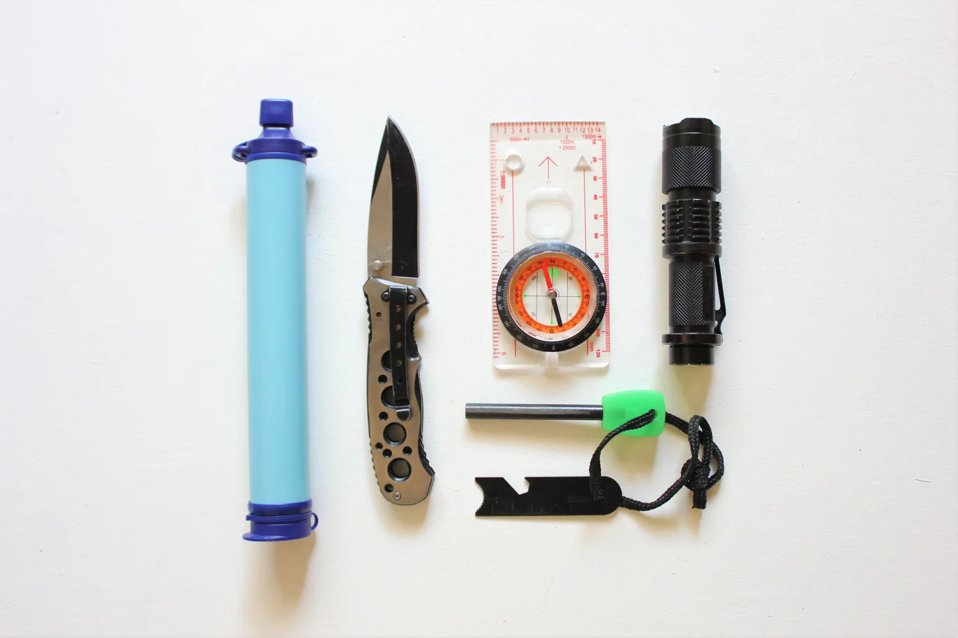 Personal straw water filter laid out with knife and other camping survival gear