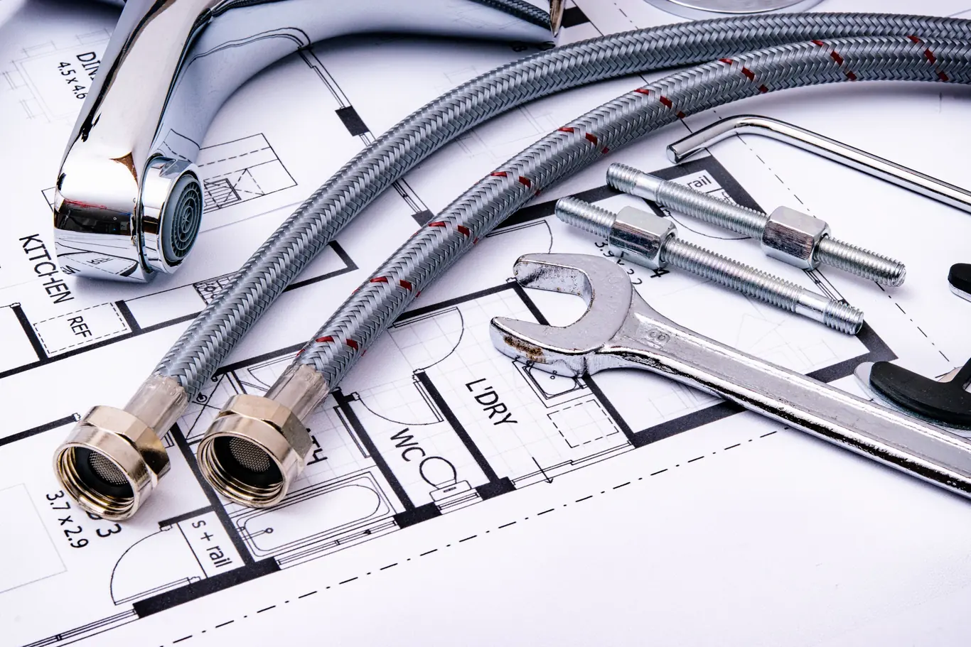 Flexible supply lines, fittings, and a wrench laid out for a plumbing installation