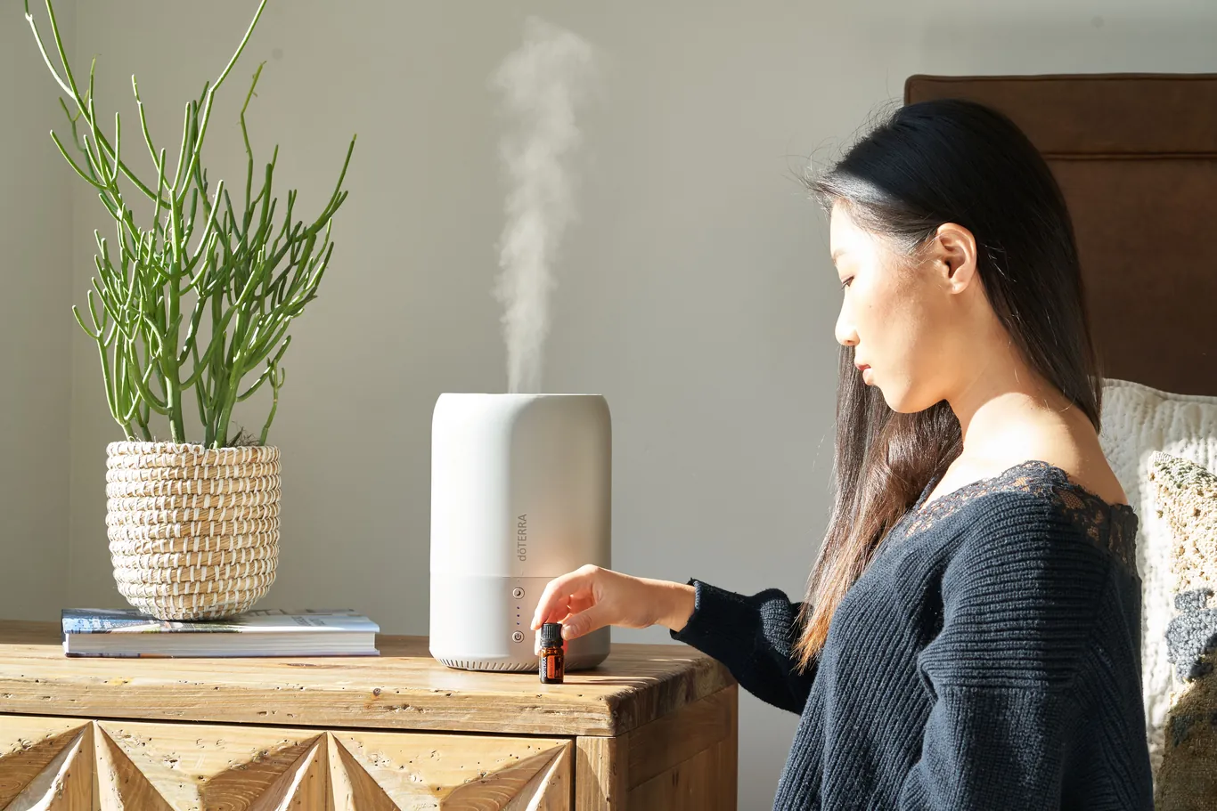A humidifier releasing visible mist on a bedside table beside a plant