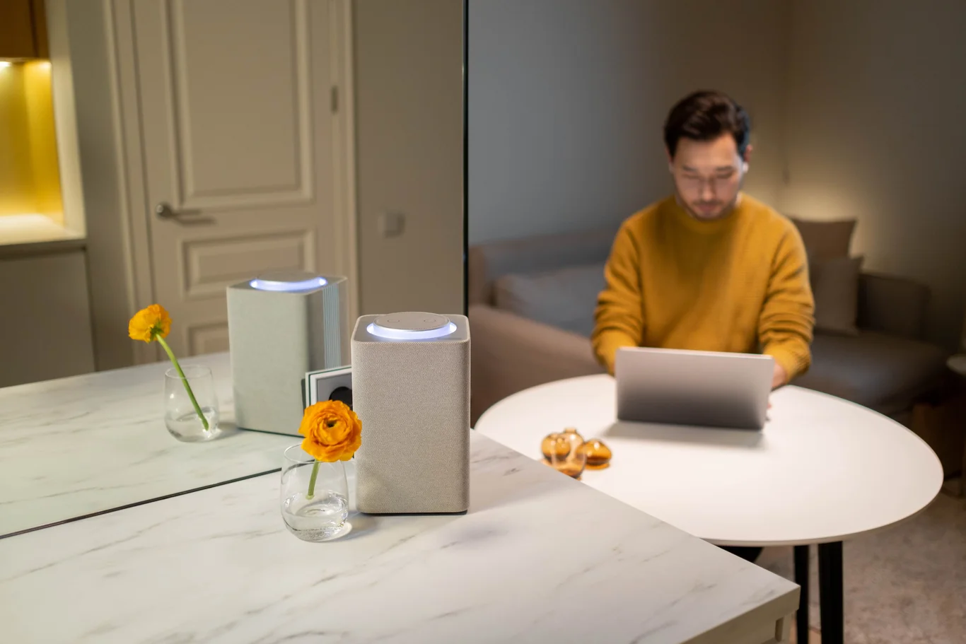 Man working at a table beside two white air purifiers in a living room
