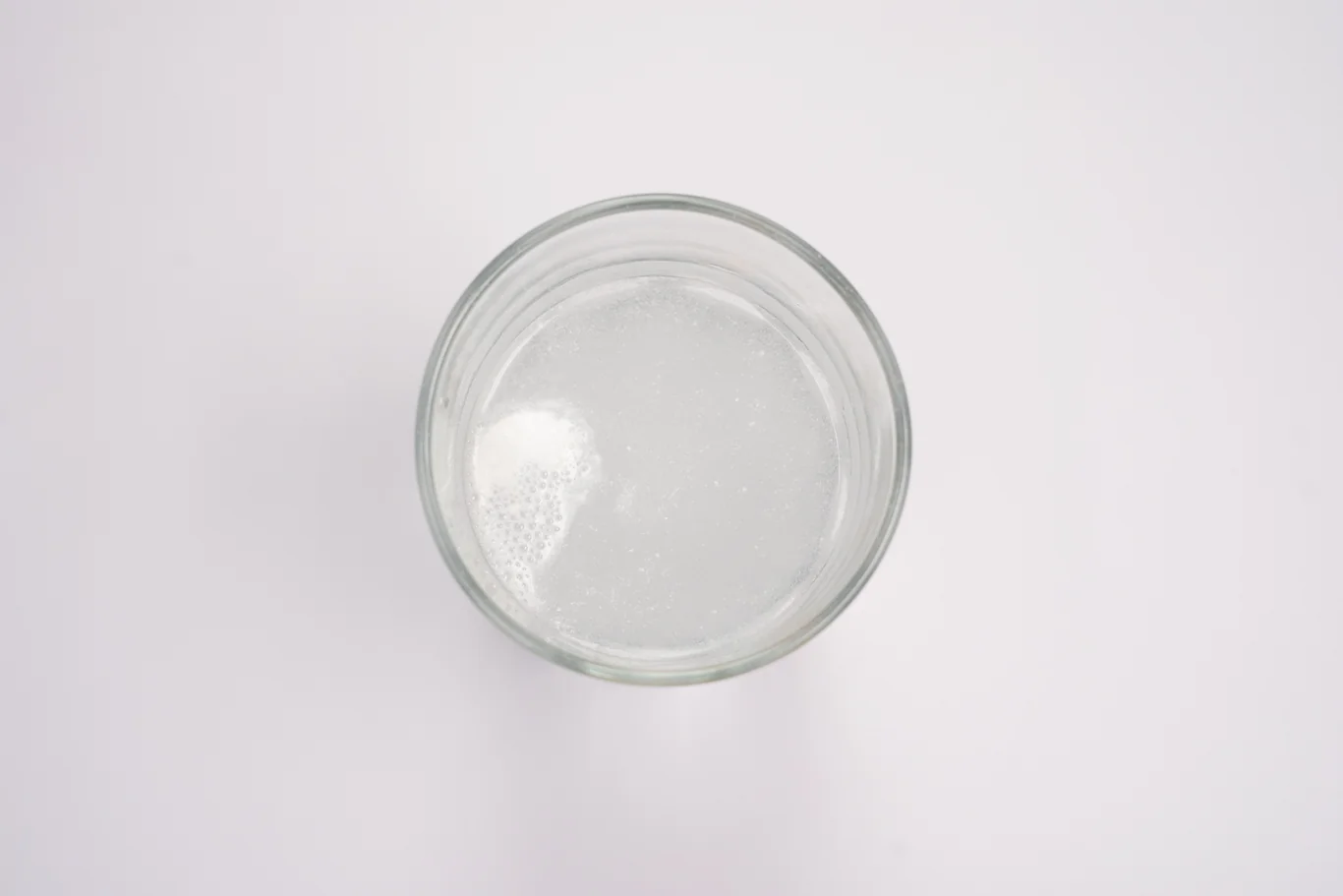 Overhead view of a glass of clear filtered water on a white surface