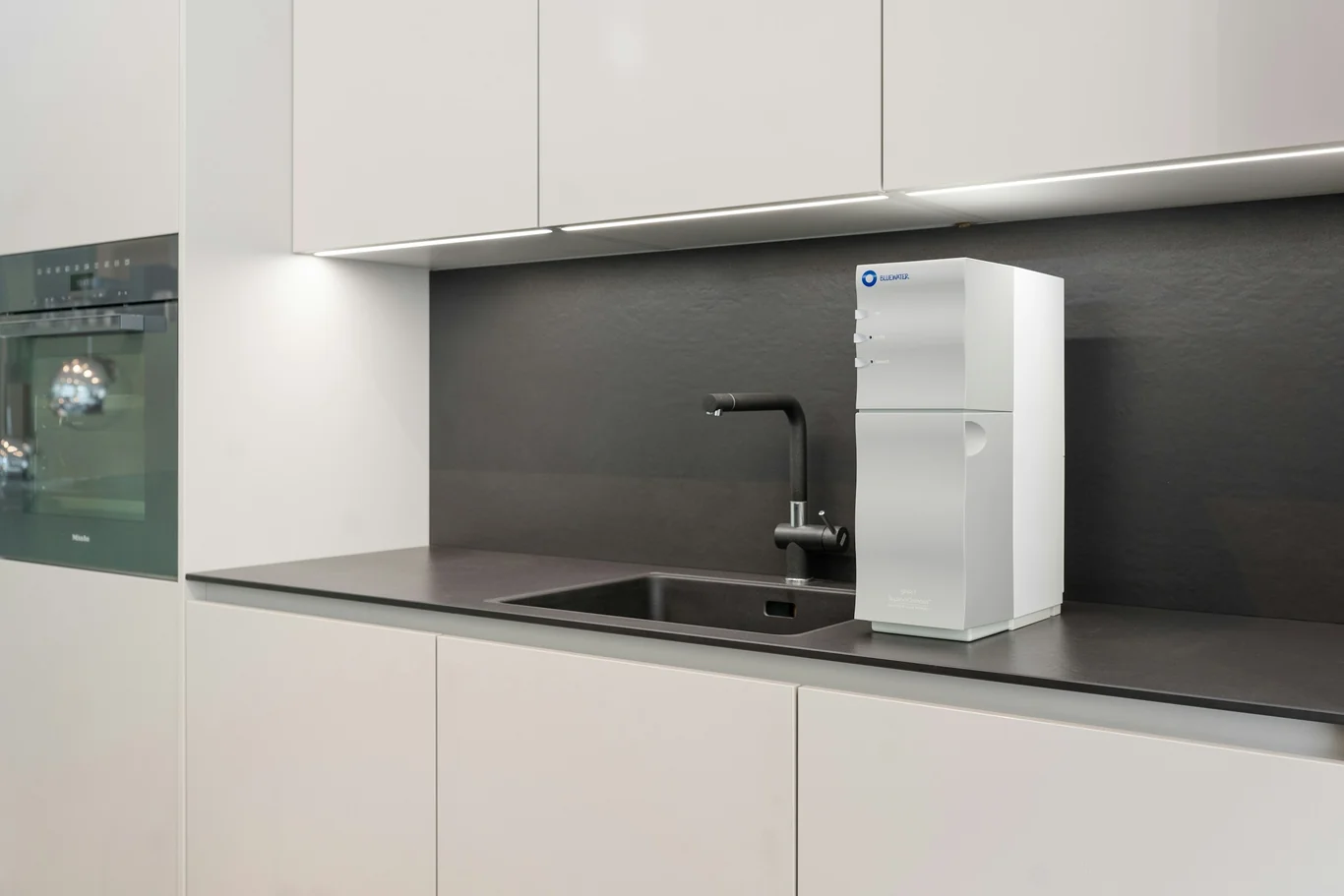 Countertop water purifier with its own dispenser tap installed in a white kitchen