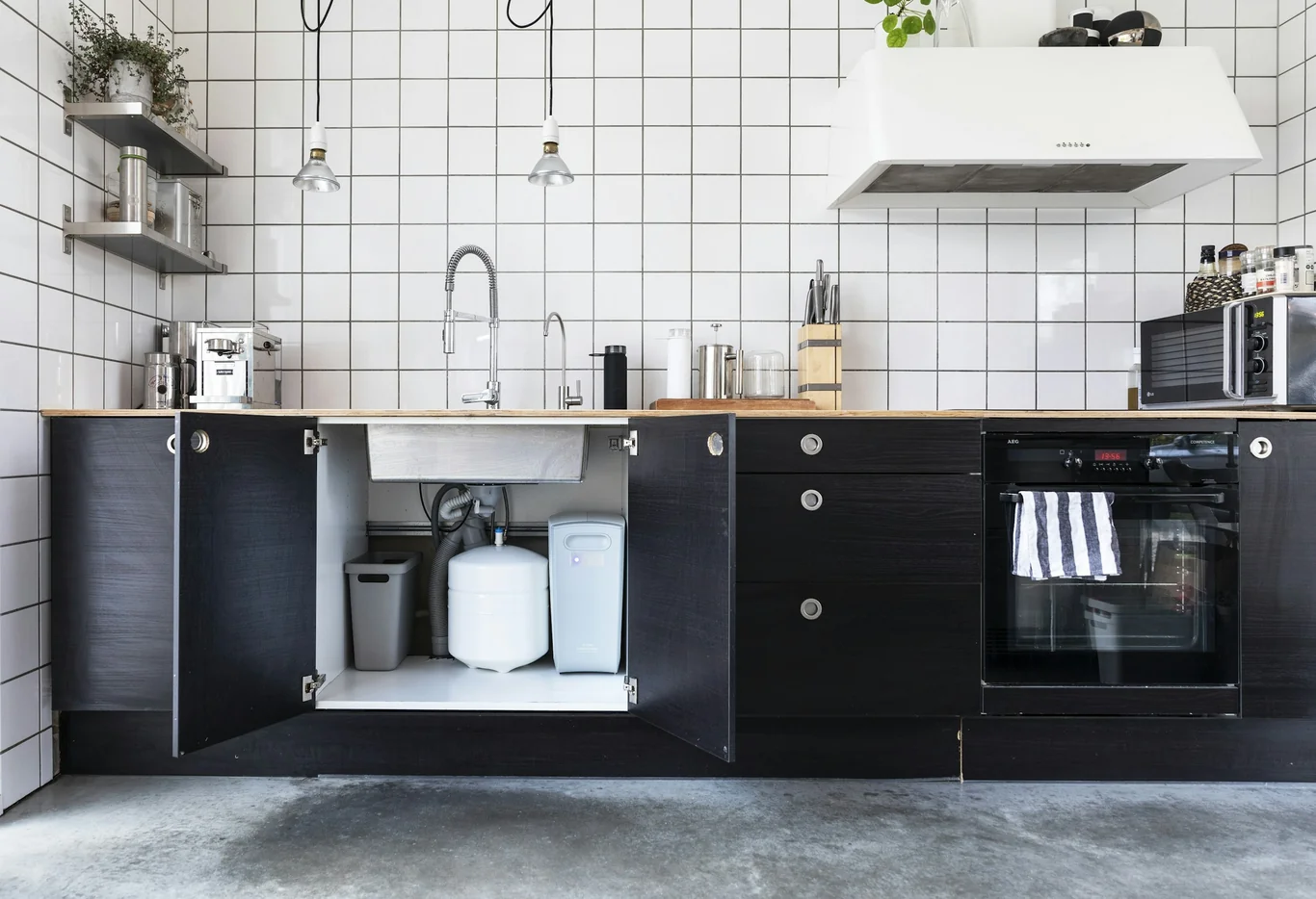 Open kitchen cabinet revealing a compact water filtration system under the sink