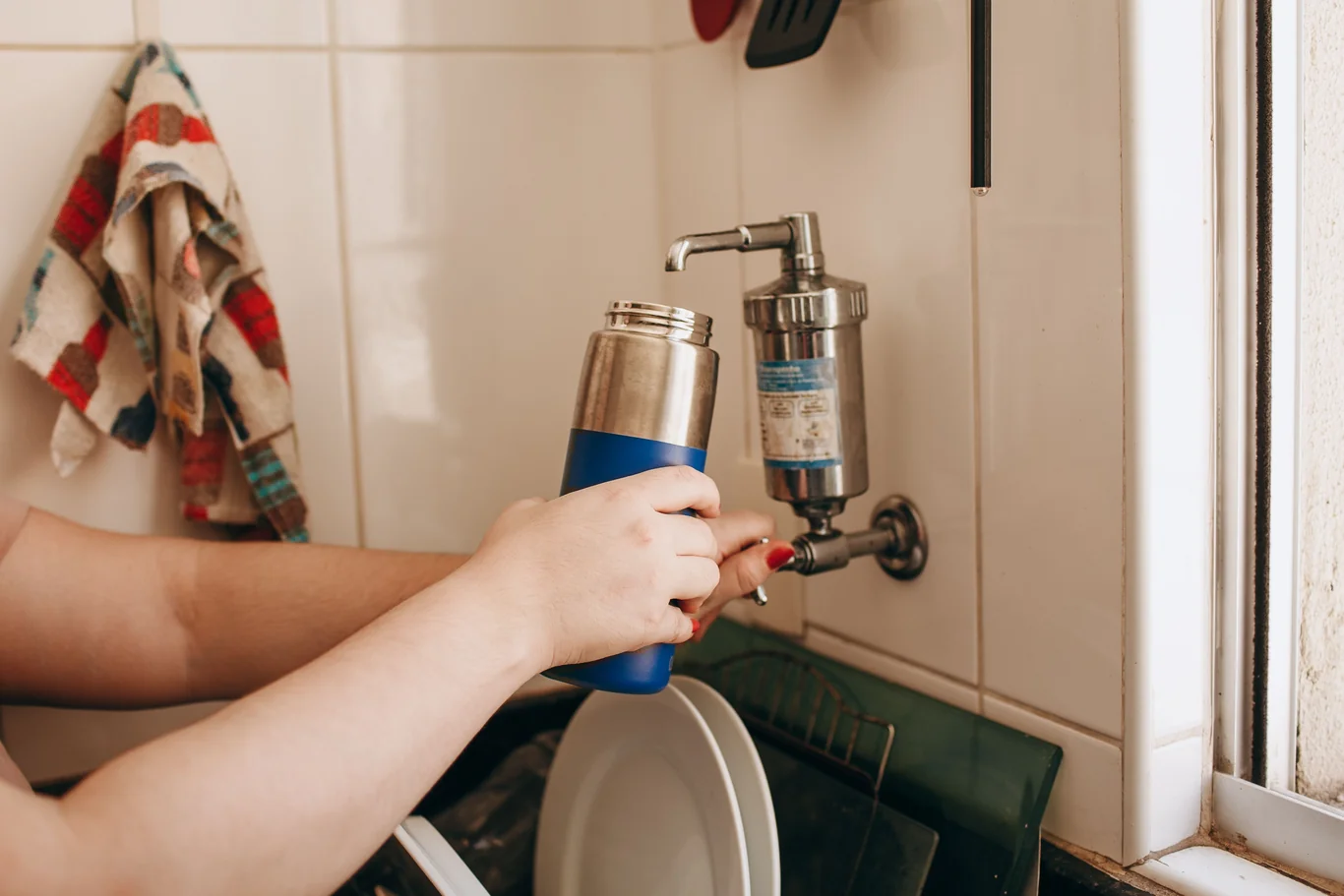 Filling a bottle from a dedicated water filter faucet mounted beside the sink