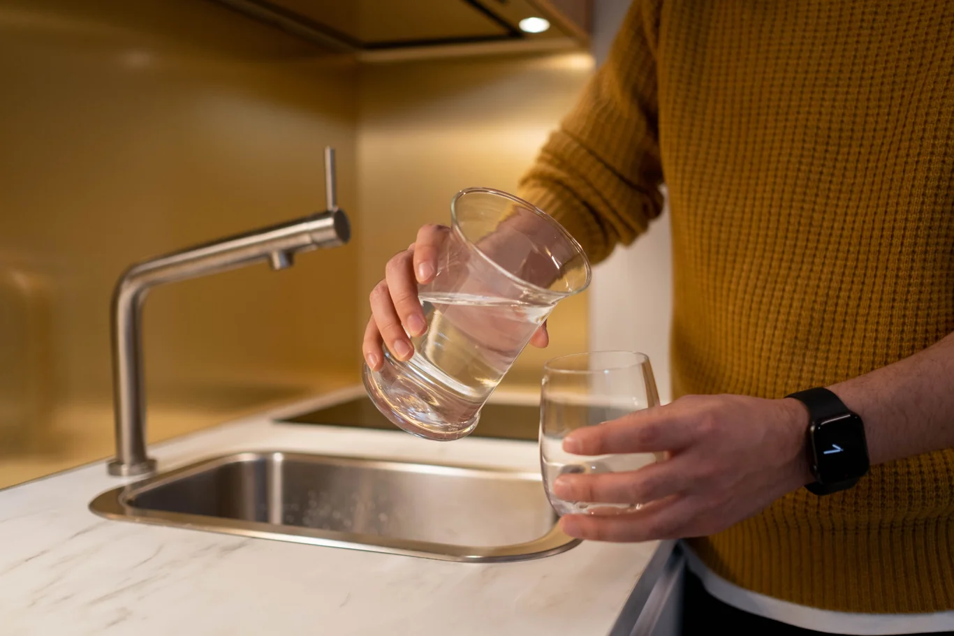 Pouring filtered water from a pitcher into a glass in a bright kitchen