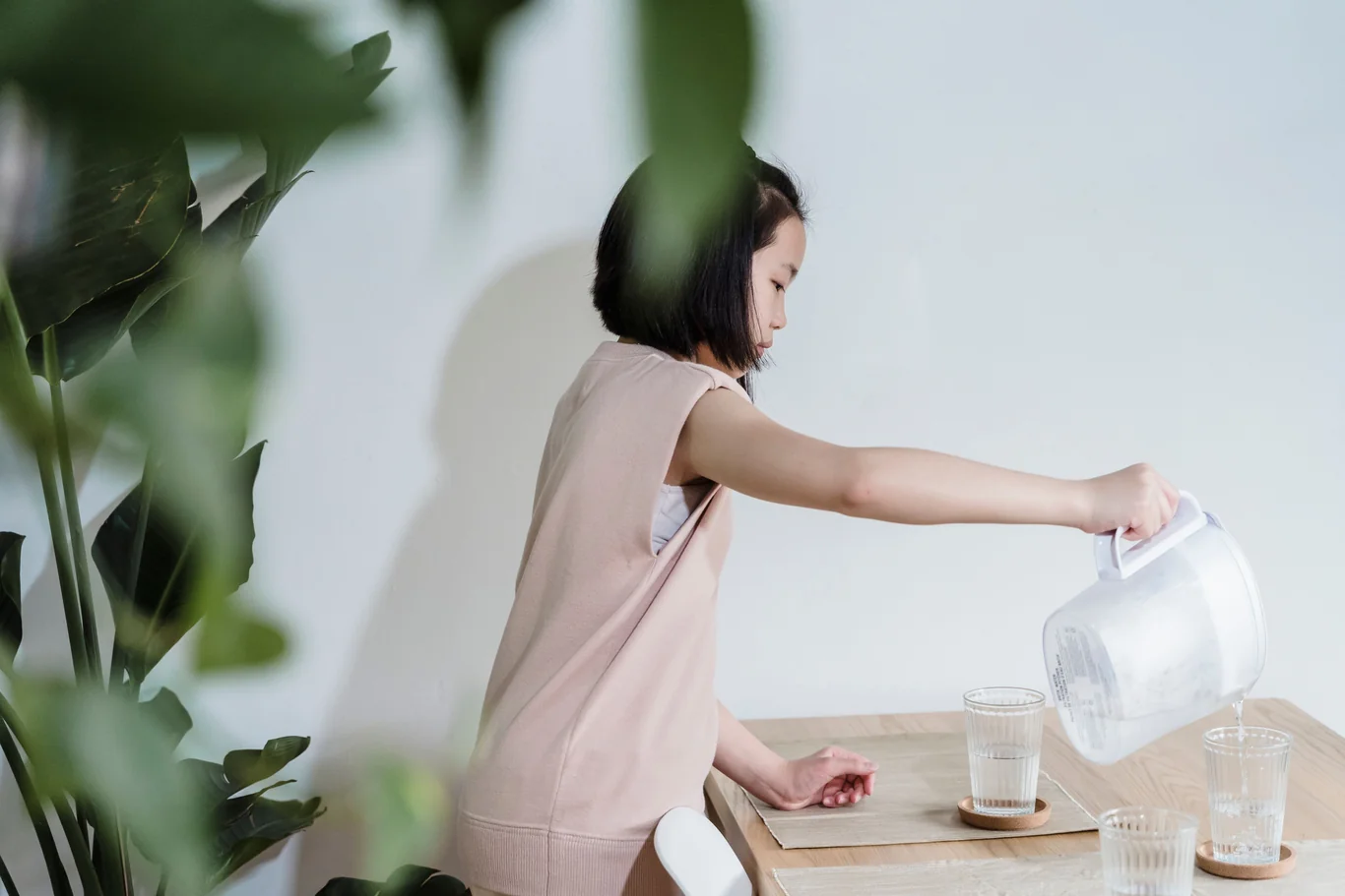 Pouring filtered water from a pitcher into a glass on the kitchen counter
