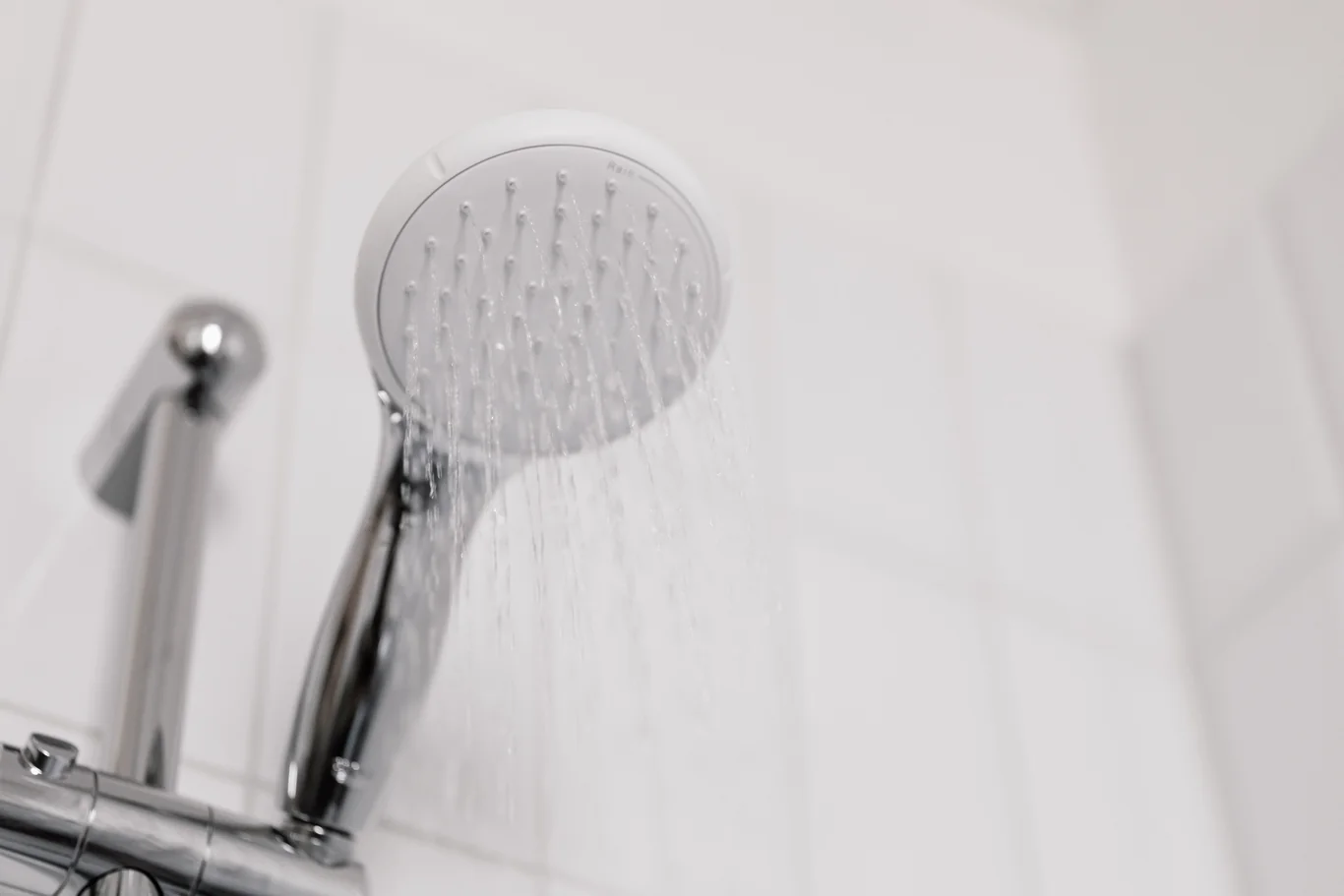 Close-up of a handheld chrome showerhead spraying water